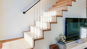 A modern staircase with wooden steps and a black handrail.