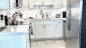 A modern kitchen with white cabinets, stainless steel appliances, and a light wood floor. - Direct waterfront home on the Gulf of Mexico. Dunedin.  (Dunedin)