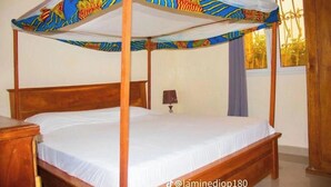 Un letto a baldacchino con una tenda colorata, una testiera in legno e un comodino.