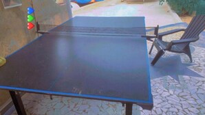 Un tavolo da ping pong con rete metallica in una zona patio esterna.