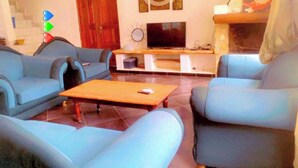 Un soggiorno con divani blu, un tavolino in legno, una televisione e un caminetto.