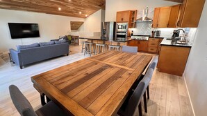 Eine moderne Küche mit Holzschränken, einer großen Kochinsel und einem Essbereich mit Holztisch und -stühlen.