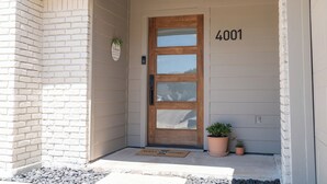 A house number 4001, a wooden front door, a welcome mat, and two potted plants. - Spacious Modern Home with Lake view in Dallas, great amenities/full Kitchen/Wifi (Garland)