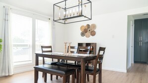 A dining area with a wooden table, six chairs, a bench, a modern chandelier, and a decorative wall piece. - Spacious Modern Home with Lake view in Dallas, great amenities/full Kitchen/Wifi (Garland)