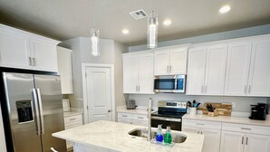 A modern kitchen with white cabinets, stainless steel appliances, and a central island with bar stools.