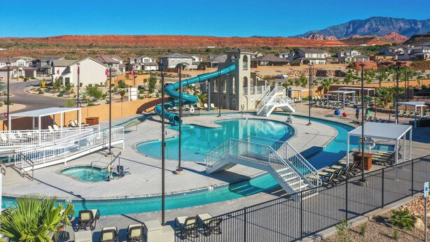 A resort with a large swimming pool, a water slide, and a view of red rock mountains.