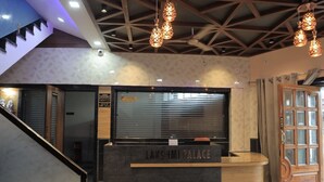 A reception desk labeled "Lakshmi Palace" with a modern design, a staircase, and a wooden door. - HOTEL LAXMI PALACE (Kekri)