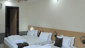 A hotel room with two beds, a ceiling fan, and a door leading to a bathroom. - HOTEL LAXMI PALACE (Kekri)