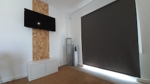A modern living room with a flat-screen TV mounted on a wooden accent wall, a sliding glass door, and a white entertainment unit. - Nature, Naturally... (Cadaval)
