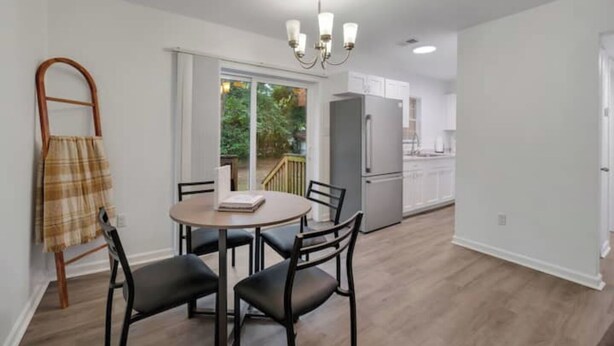 Una cocina moderna con armarios blancos, un refrigerador gris y un comedor con una mesa redonda y cuatro sillas.