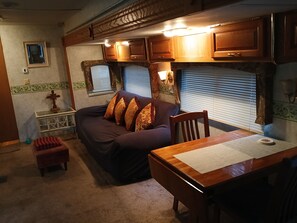 A cozy RV interior with a sofa, a small table, and a window with blinds.