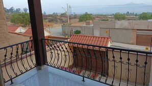 A balcony with a metal railing overlooking a residential area with houses and a distant mountain. - Hermosa casa cómoda, espaciosa y con todas las comodidades  (Cochabamba)