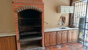 A kitchen with a brick oven, wooden cabinets, a sink, and a tiled floor. - Hermosa casa cómoda, espaciosa y con todas las comodidades  (Cochabamba)