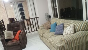 A living room with a brown armchair, a striped sofa, and a fan. - Hermosa casa cómoda, espaciosa y con todas las comodidades  (Cochabamba)