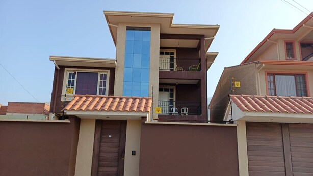 A modern two-story house with a balcony, a garage, and a tiled roof. - Hermosa casa cómoda, espaciosa y con todas las comodidades  (Cochabamba)