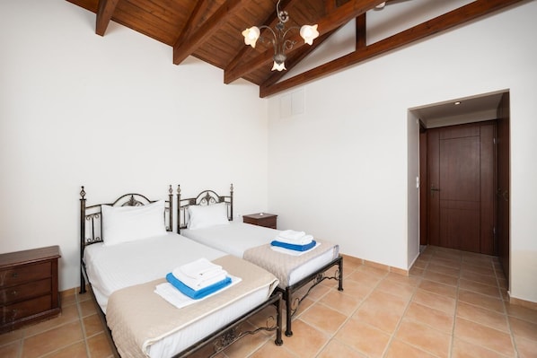 Une chambre avec deux lits, des poutres en bois au plafond et une porte sur le côté droit.