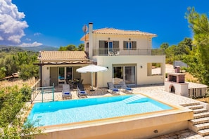Une maison à deux étages avec une piscine, un espace extérieur aménagé et un coin barbecue.