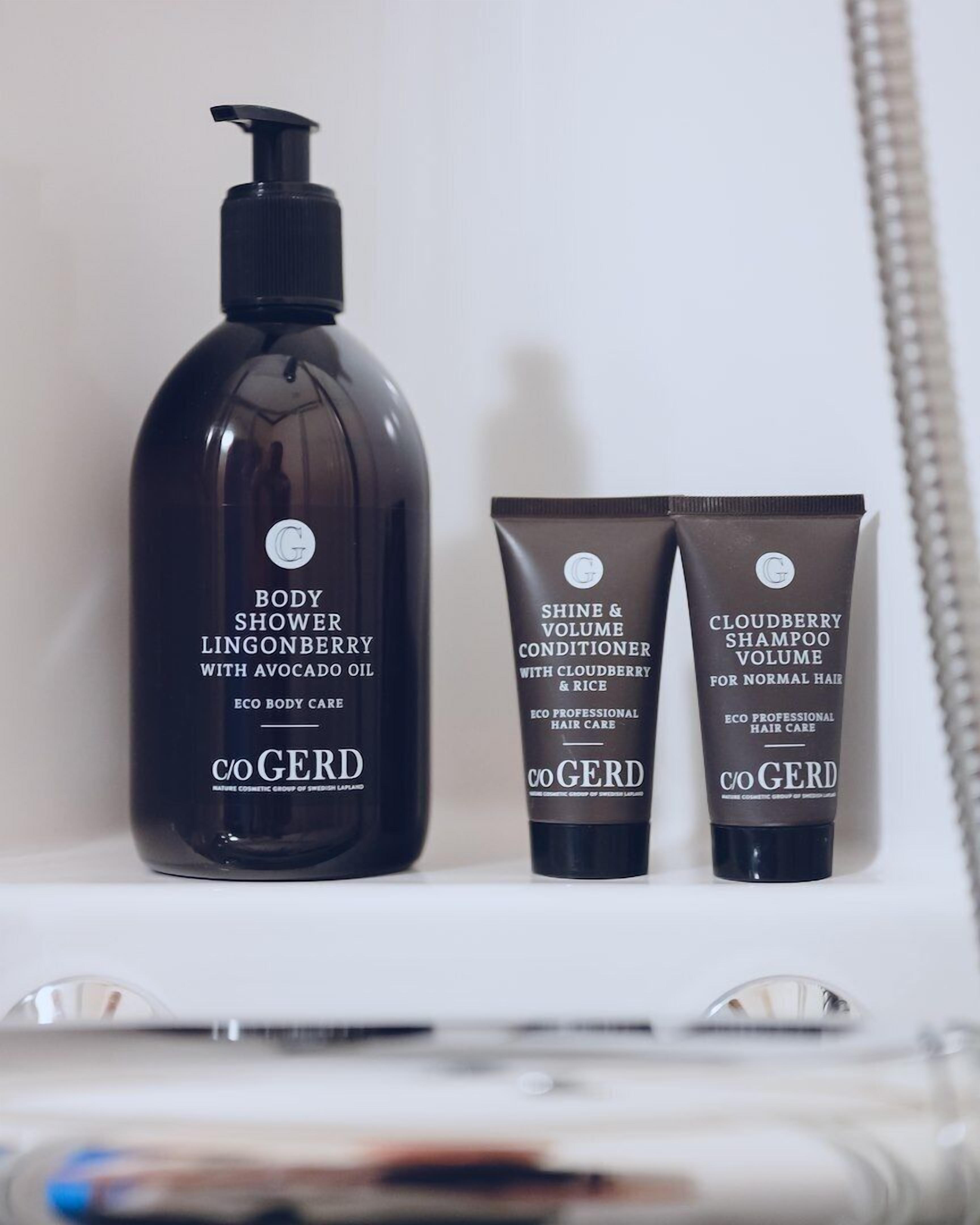A bathroom with a bottle of body shower lingonberry with avocado oil, a tube of shine & volume conditioner with cloudberry & rice, and a tube of cloudberry shampoo volume for normal hair.