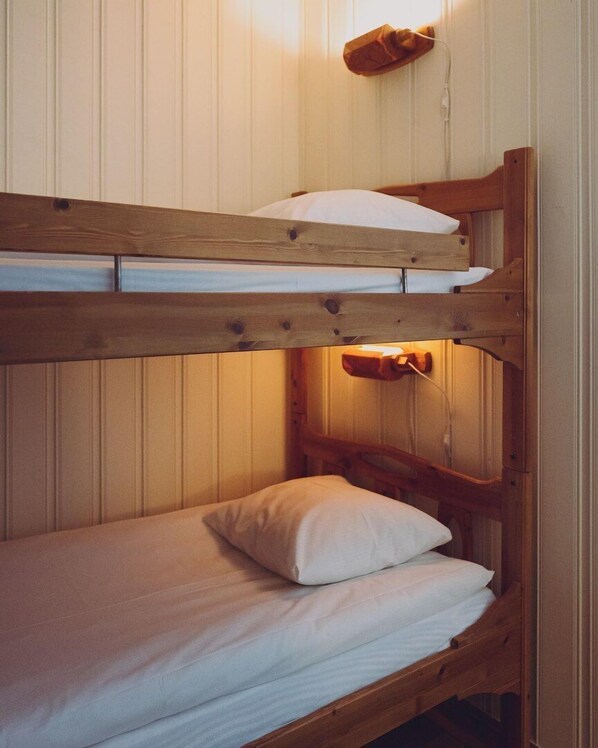 Una cama litera con estructura de madera y ropa de cama blanca.