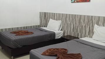 Habitación de hotel con dos camas individuales, cabecera a rayas grises y blancas, un cuadro abstracto de colores y una unidad de aire acondicionado instalada en el techo.
