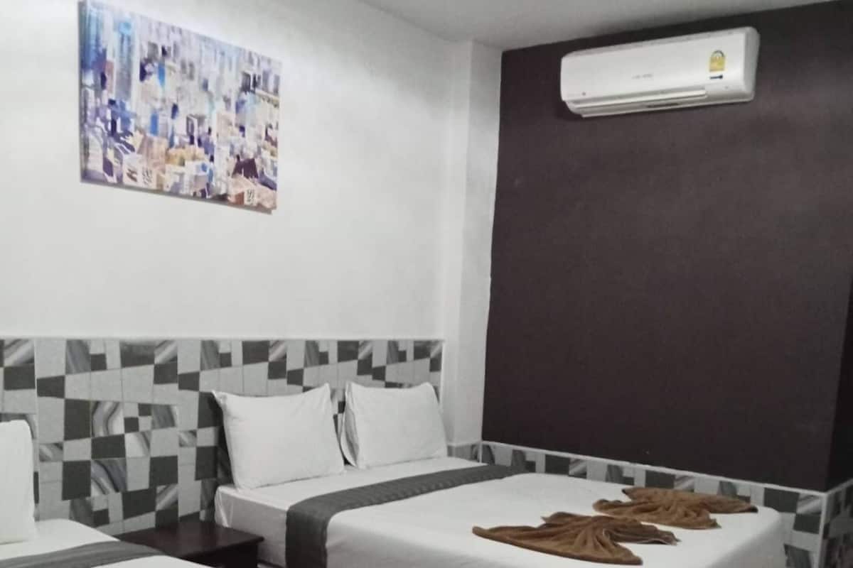A hotel room with two beds, a checkered headboard, a wall-mounted air conditioner, and a colorful abstract painting.