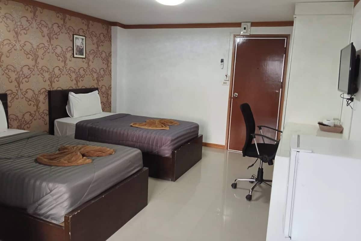 A hotel room with two beds, a desk, a chair, a television, and a door.