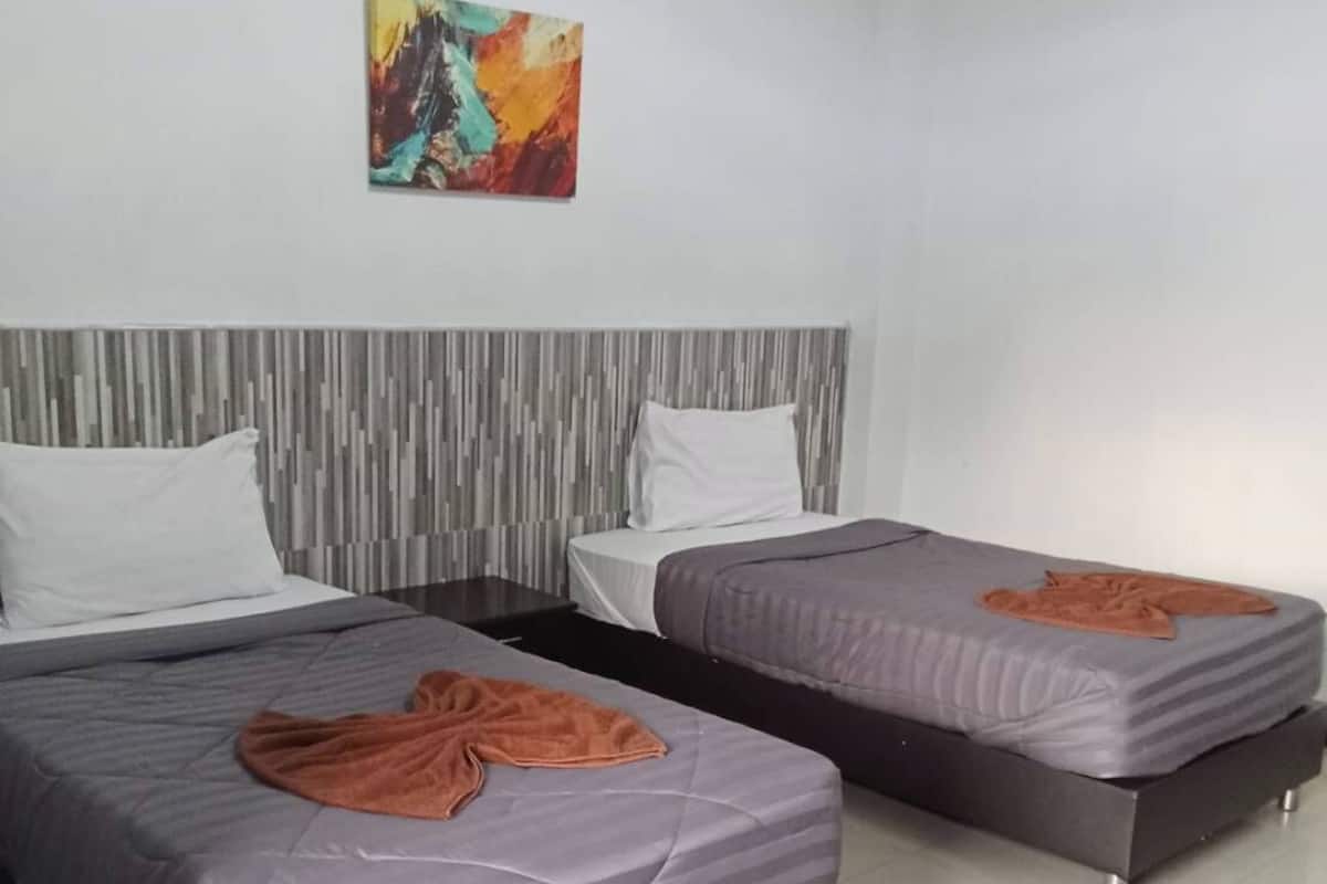 A modern hotel room with two single beds, a grey striped headboard, and a colorful abstract painting on the wall.