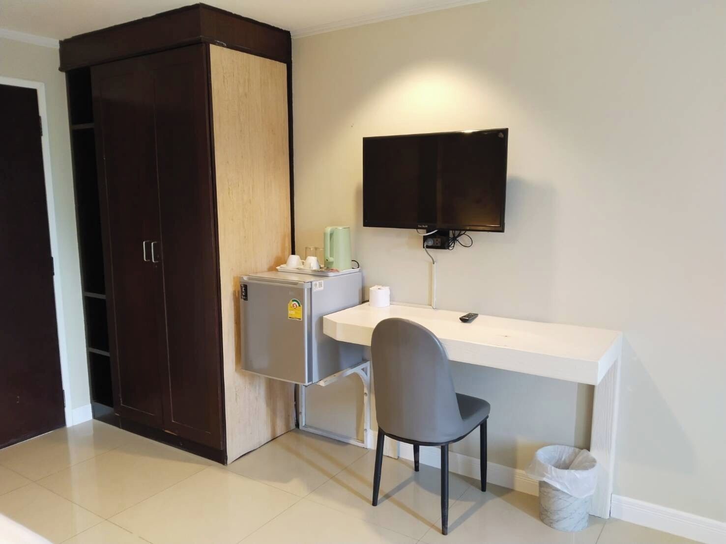 Una habitación compacta con kitchenette, un escritorio, una silla, un televisor y un armario.