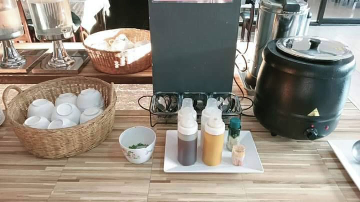 Un plan de travail de cuisine avec une machine à café, une bouilloire, une grande casserole, un panier de tasses et des condiments.