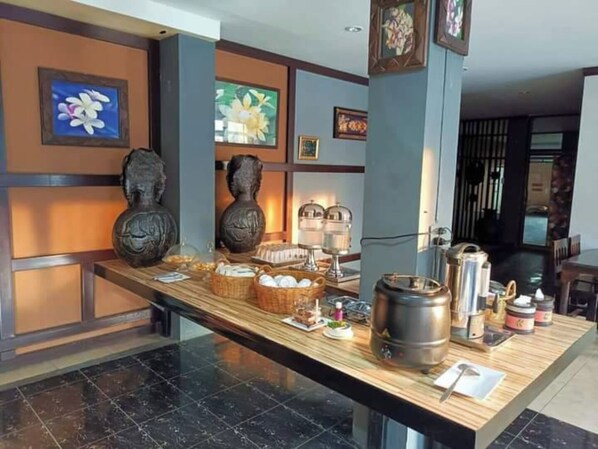 Una barra de desayuno con diversas comidas y condimentos, obras de arte enmarcadas en las paredes y una decoración interior moderna.
