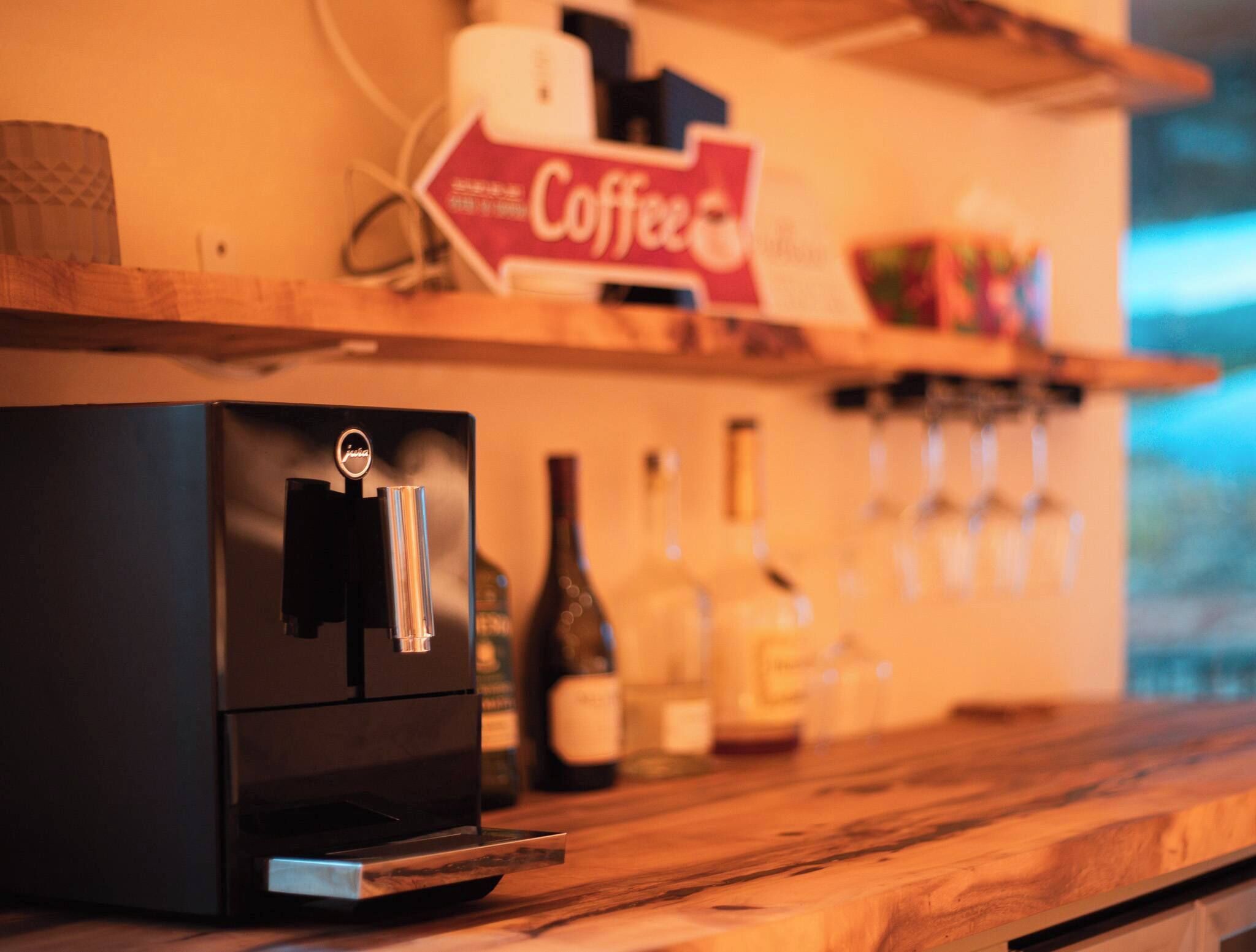 A coffee machine on a wooden counter with a sign reading "Coffee" above it.