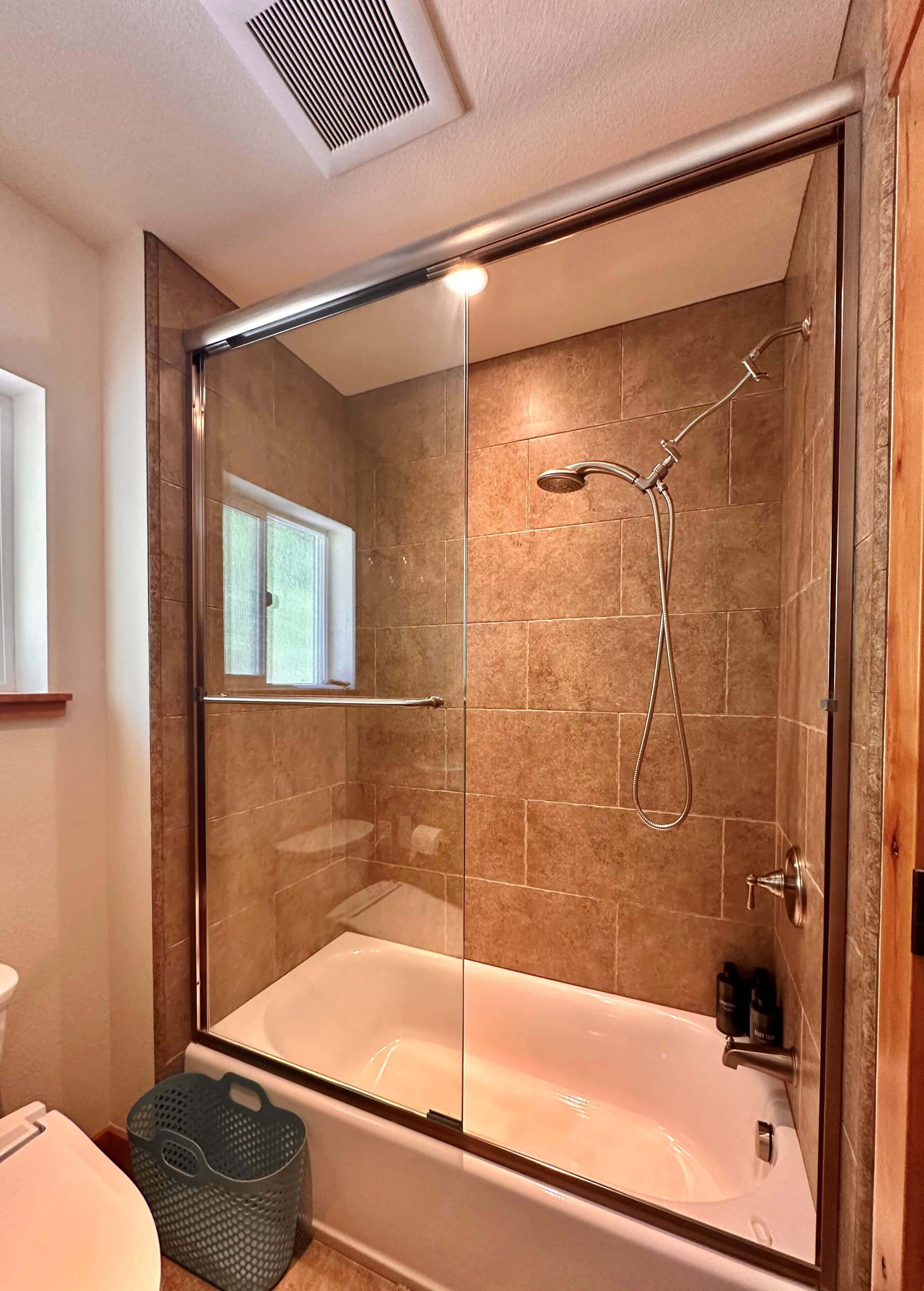 A modern bathroom with a glass-enclosed shower, a bathtub, and a toilet.