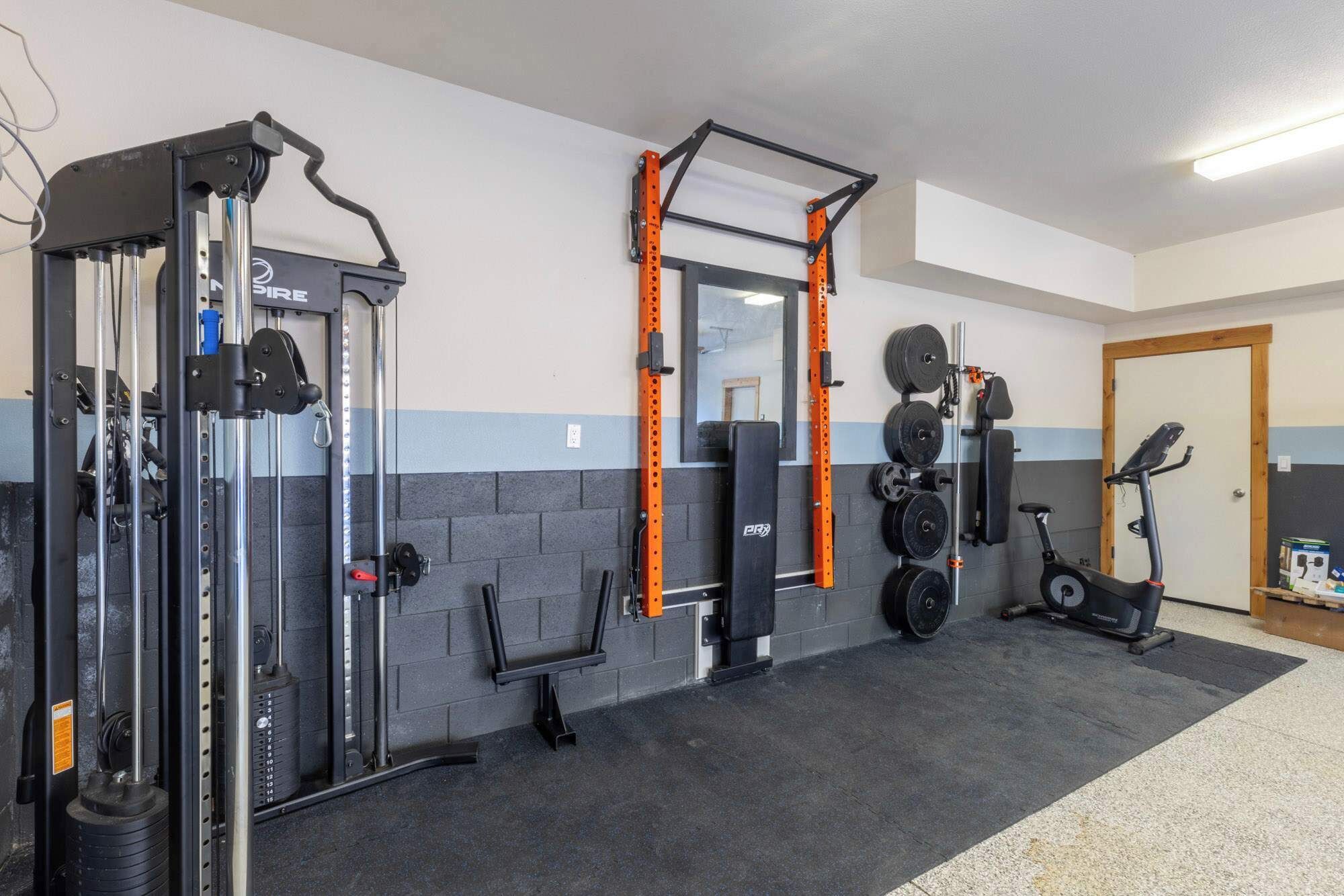 A gym with weightlifting equipment, a pull-up bar, and an exercise bike.
