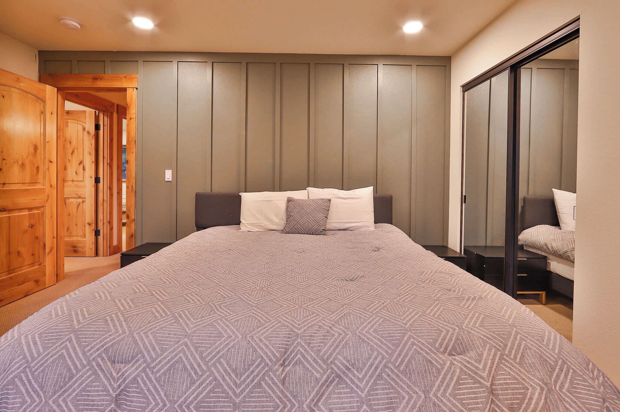 A bedroom with a large bed, wooden wardrobe, and a sliding door closet.