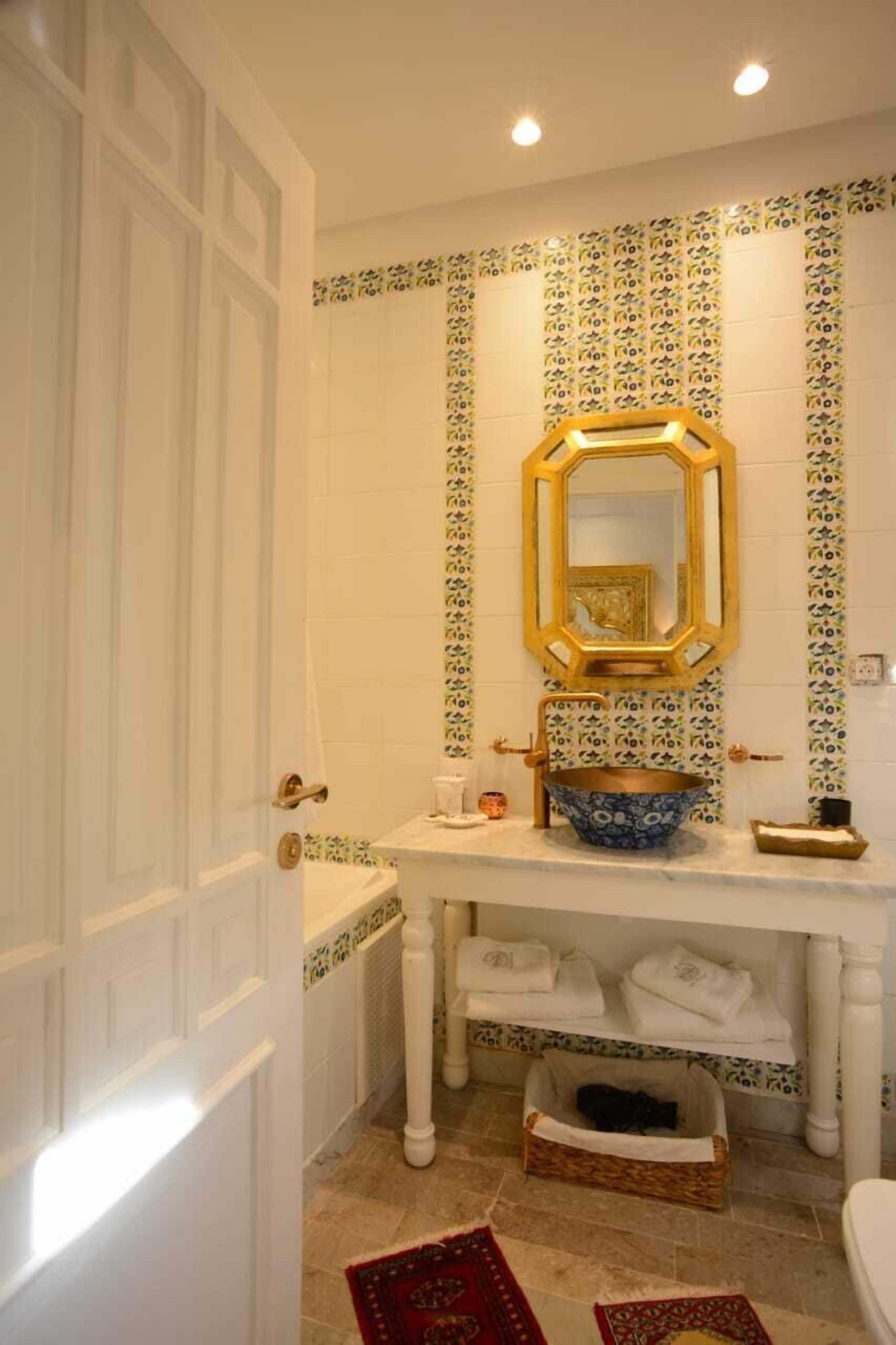 A bathroom with a white sink, a mirror with a hexagonal frame, and a tiled backsplash.