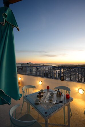 A balcony with a table set for two, overlooking a cityscape during sunset. - Dar Essalem (Sidi Bou Said)