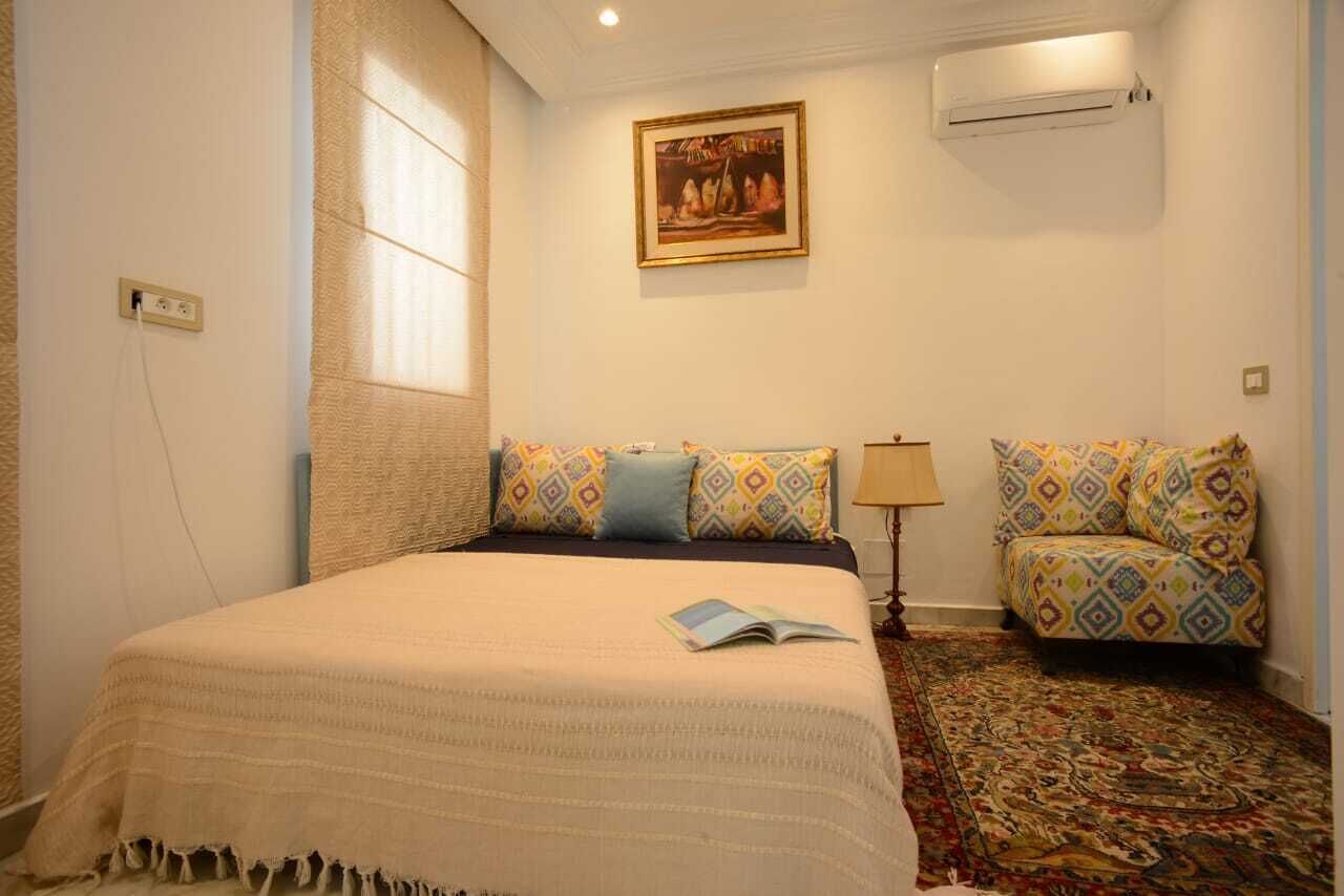 Een slaapkamer met een bed, een gestreept sofa, een schilderij aan de muur en een airconditioner.