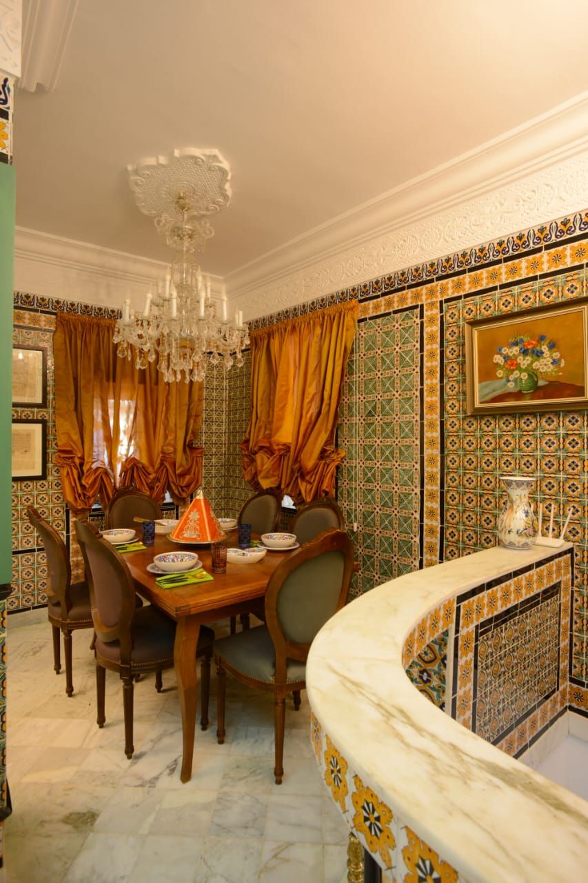 A dining area with a marble table, chairs, and a chandelier.
