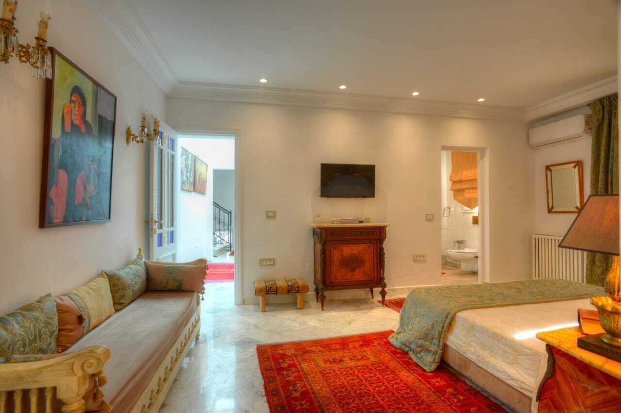Een ruime kamer met een groot bed, een bank, een tafeltje, een schilderij en een televisie.