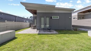 Une maison moderne dotée d’un patio, d’un espace salon couvert et d’un petit jardin.