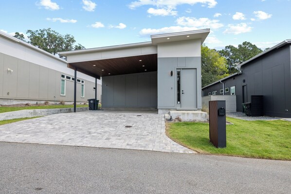 Un bâtiment moderne doté d’une entrée abritée, d’une allée pavée et d’un petit espace verdoyant.