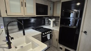 A compact kitchen with a sink, stove, microwave, and cabinets. - RV in Lakeland, near Orlando & Ocala  (Lakeland)