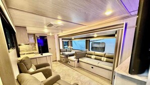 A modern RV interior with a kitchen area, seating, and a large window. - RV in Lakeland, near Orlando & Ocala  (Lakeland)