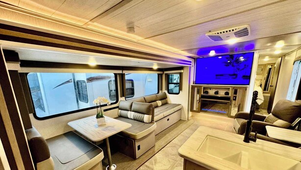 A modern RV interior with a dining area, seating, and a kitchenette. - RV in Lakeland, near Orlando & Ocala  (Lakeland)