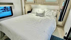A bedroom with a bed, a television on the wall, and a window. - RV in Lakeland, near Orlando & Ocala  (Lakeland)