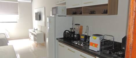 A modern kitchen with white cabinets, a black countertop, and a built-in microwave.