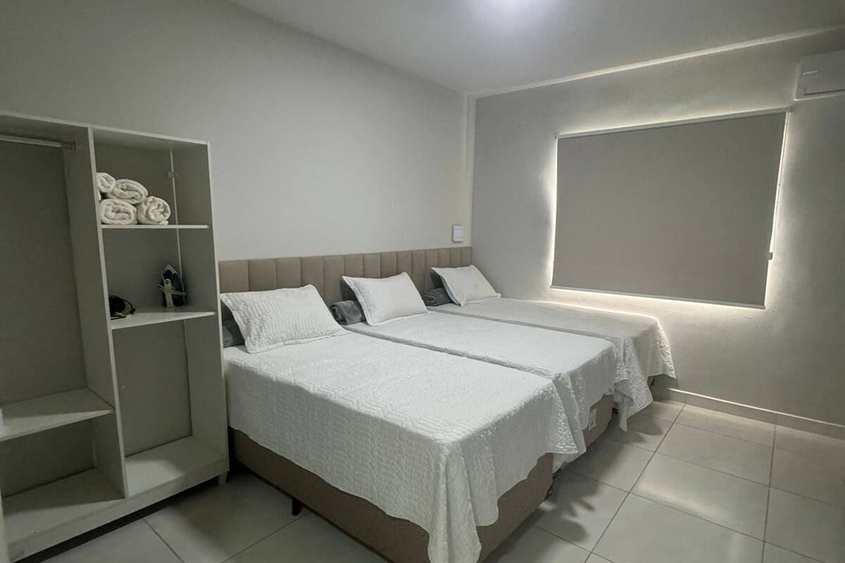 Un dormitorio con dos camas, un armario y una ventana.