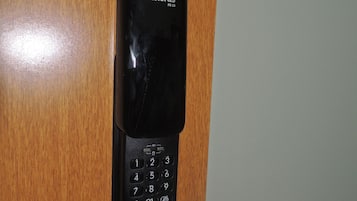 Een zwart intercomapparaat bevestigd aan een houten deur, met een numeriek keypad en een luidsprekerrooster.