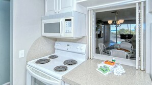 A compact kitchen with a stove, microwave, and a small dining area with a view. - Sunny Siesta Key 1 Bed 1 Bath with Gulf Views  Steps to Beach (Siesta Key)