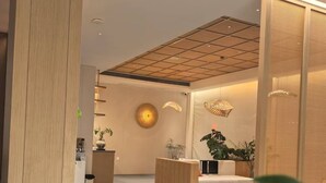 Ein moderner Empfangsbereich mit einem Holzbüro, einer Sitzecke und einer Decke mit eingelassener Beleuchtung.